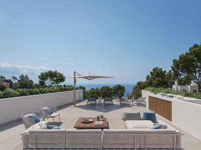 Amplia terraza moderna con sofás, zona de estar, tumbonas y vistas despejadas al mar bajo un cielo azul.