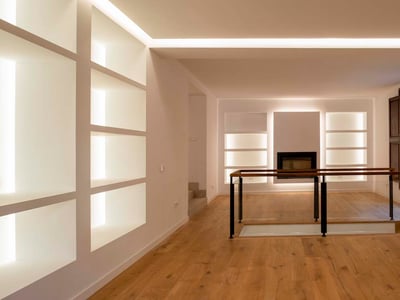 Minimalistisches Interieur mit Eichenparkett, weißen Wänden mit beleuchteten Nischen und Glasgeländer.