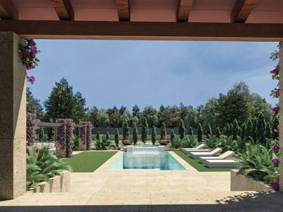 Vista de una piscina turquesa desde una terraza con columnas de piedra, rodeada de césped y buganvillas.