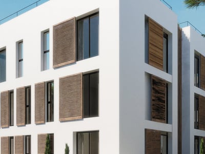 Modern vit byggnad med träjalusier och stora fönsterpartier under en blå himmel.