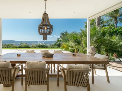 Ansicht eines modernen Pools, umgeben von üppiger Vegetation und einem Haus mit großen Fenstern. Minimalistisches Design.
