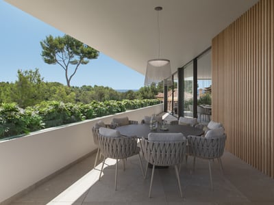 Terraza moderna con mesa de comedor redonda, sillas tejidas, pared de madera y vistas a la vegetación y el mar.