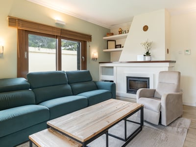 Modernt vardagsrum med blågrön soffa, vit inbyggd öppen spis, soffbord i trä och beige fåtölj.