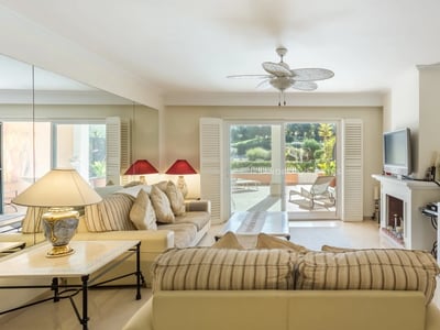 Geräumiges Wohnzimmer mit Sofas, Kamin, Deckenventilator und Schiebetüren zum Garten.