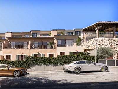 Vista exterior de residencias mediterráneas con muros de piedra, balcones y coches aparcados en la calle.