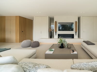 Salón espacioso con sofás en beige, chimenea integrada y una mesa de centro moderna en tonos neutros.