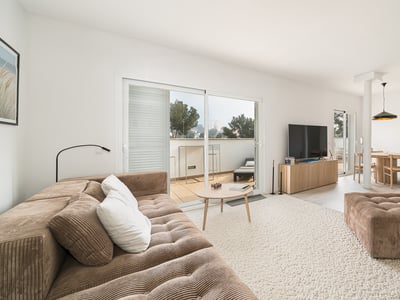 Modern living room with a brown corduroy sofa, large rug, and sliding glass doors leading to a sunlit terrace.