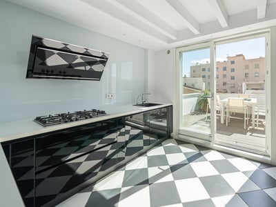Modern kitchen with black and white checkered floor, glossy black cabinets, and a glass door leading to a sunny terrace.