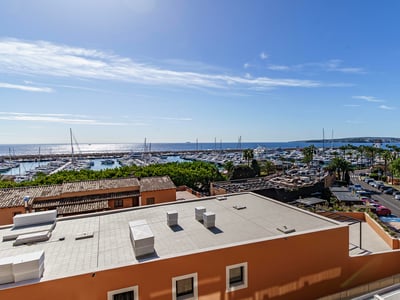 Vue surélevée surplombant un port de plaisance avec des yachts et la mer Méditerranée sous un ciel bleu clair.