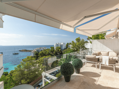 Moderne Terrasse mit beigen Sofas, Glasgeländer und Panoramablick auf das Meer unter Markisen.