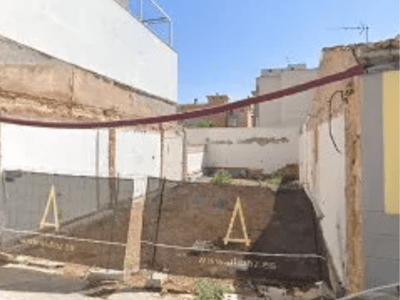 Ansicht eines Baugrundstücks mit Bauzaun und sichtbaren weißen Begrenzungsmauern.