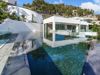 Piscine à débordement moderne aux eaux cristallines surplombant une villa blanche minimaliste nichée dans une colline.