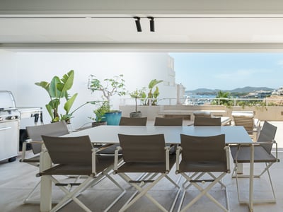 Terraza moderna con zona de comedor, barbacoa y vistas panorámicas al mar y a la costa.