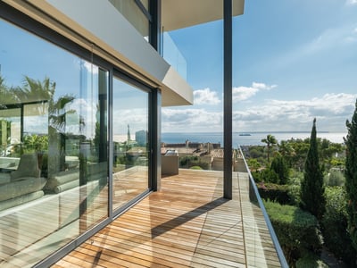 Terrasse moderne en bois avec garde-corps en verre offrant une vue panoramique sur la mer Méditerranée.