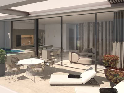 Terraza moderna con zona de comedor, tumbonas y pequeña piscina junto a salón y cocina con paredes de cristal.