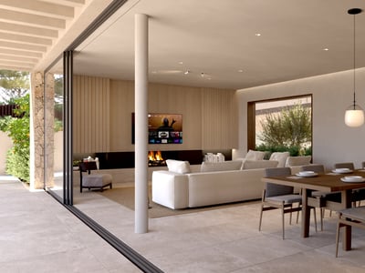 Modern open-plan room with large dining table, white sectional sofa, fireplace, and floor-to-ceiling glass doors.