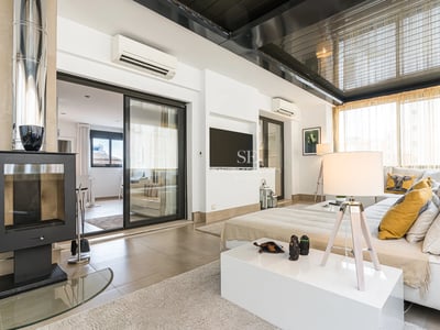 Geräumiges Wohnzimmer mit Kamin, großen Fenstern und Zugang zu einer Terrasse mit Aussicht. Moderne Dekoration in neutralen Tönen.