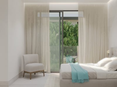 Modernt sovrum med knapphäftad sänggavel, turkos pläd, fåtölj och stora fönster som vetter mot grönska.