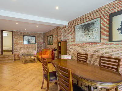 Essbereich mit Holztisch und orangefarbenem Sofa vor einer Wand aus Sichtziegeln in einem gemütlichen Innenraum.