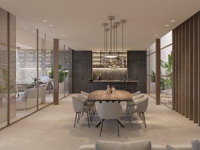 Elegante comedor con mesa de madera, lámparas de diseño y paredes de cristal con vistas al jardín interior.