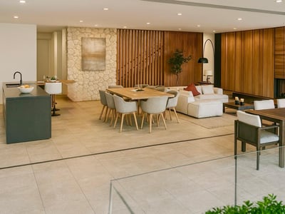 Amplio interior moderno con pared de piedra, mesa de comedor de madera, sofá blanco y una acogedora chimenea al fondo.