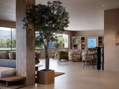 Modernt vardagsrum med designfåtöljer, ett stort inomhusträd och fönster från golv till tak med utsikt över grönska.