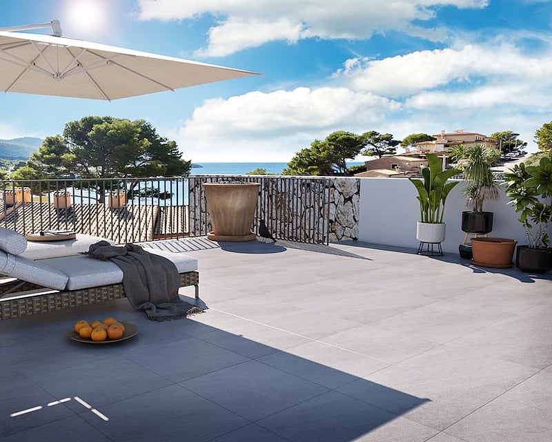 Sunny terrace with lounge chairs, large umbrella, and panoramic sea and mountain views.