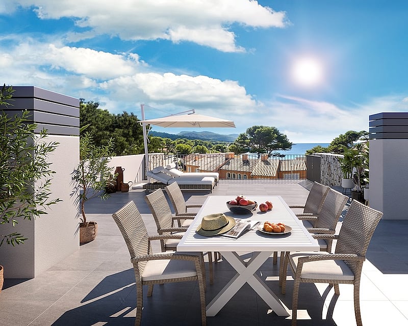Sun-drenched rooftop terrace with white dining set, lounge chairs, and a panoramic view of the sea and coastal hills.