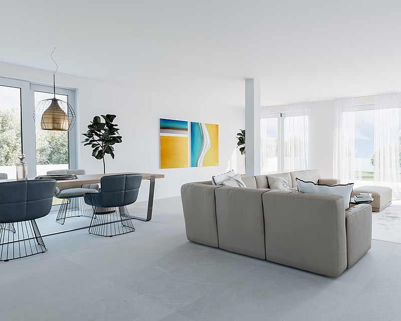 Bright minimalist living room with beige sofa, blue dining chairs, and large windows overlooking a garden.