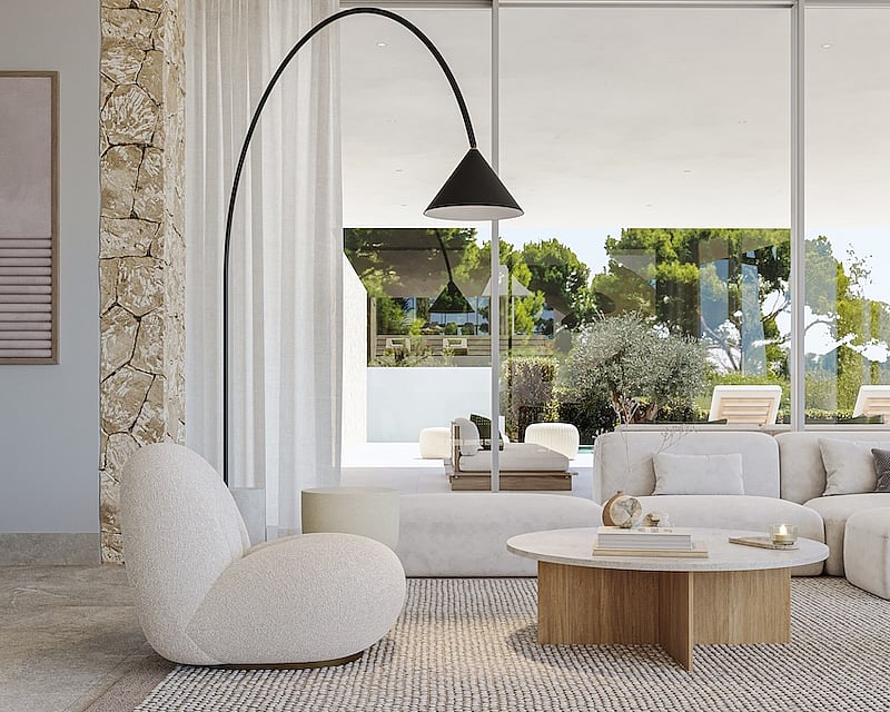 Salón luminoso con muebles de tejido bouclé, pared de piedra natural y grandes ventanales con vistas al jardín.