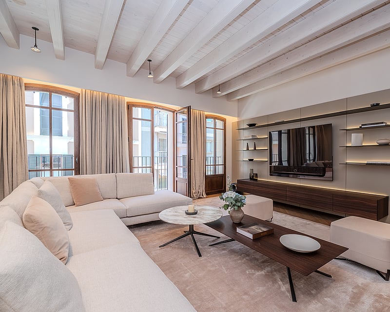 Modern luxury living room featuring exposed white beams, cream L-shaped sofa, and bespoke walnut media unit.