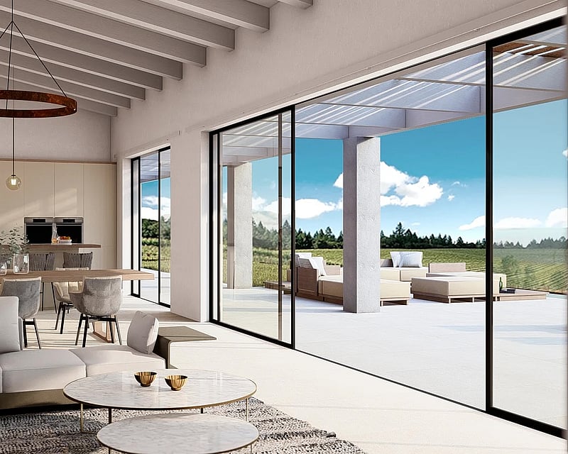 Bright living room with wooden beams, modern sofas, and large glass sliding doors opening to a sunny terrace.
