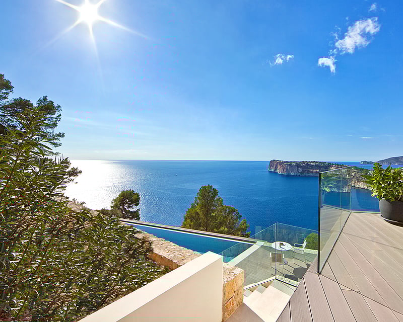 Modern terrace with glass railings overlooking the Mediterranean Sea and an infinity pool.