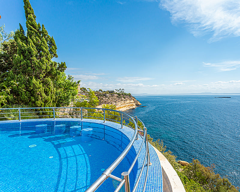 Spacious balcony with sea view, modern furniture, glass railing. Bright and elegant space. Architectural design details.