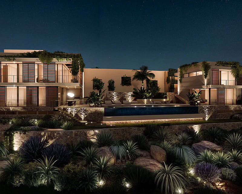 Night view of a luxury multi-level villa with illuminated infinity pool, stone walls, and large glass windows.