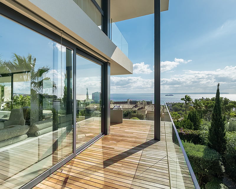 Modern wooden terrace with glass railings and panoramic views of the Mediterranean Sea.