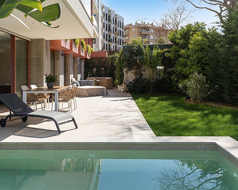 Luxury outdoor terrace featuring a private plunge pool, dining area, and manicured lawn surrounded by greenery.