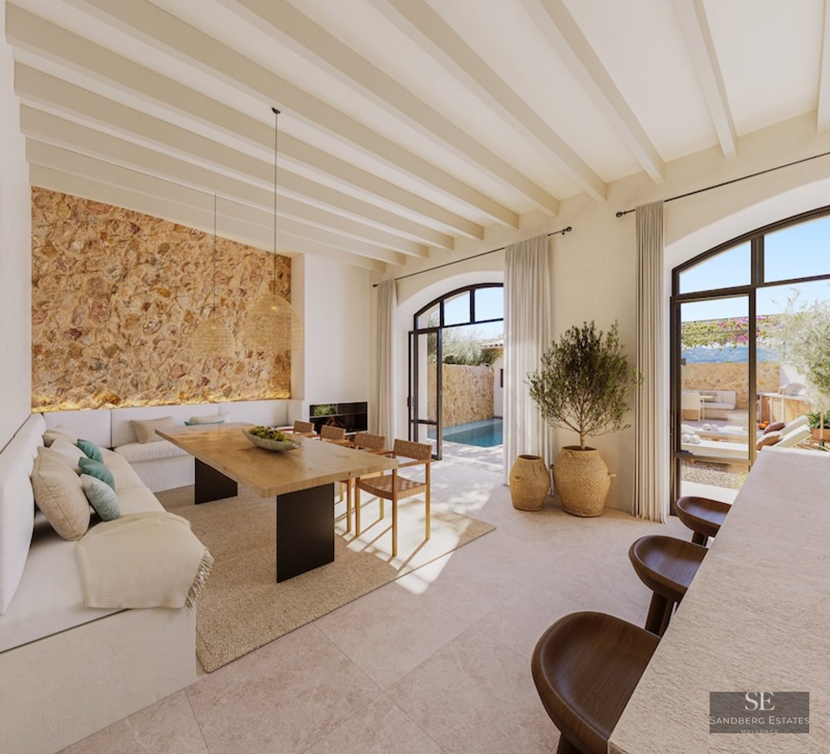 Modern Mediterranean dining room with stone wall, wooden table, and arched doors opening to a pool area.