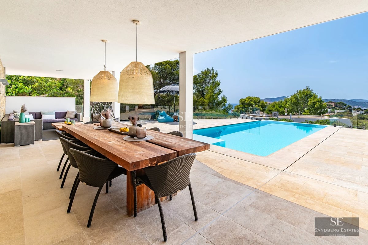 Spacious living room with picture windows, beige sofas, and a wooden coffee table. Panoramic sea views from the balcony. Modern and bright design.