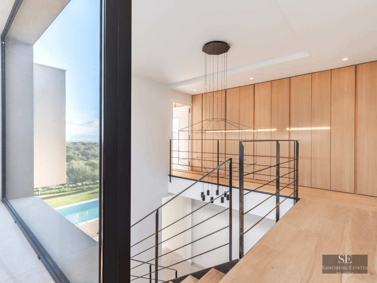 Interior view of a wooden landing with metal railings and a large window overlooking an outdoor swimming pool.