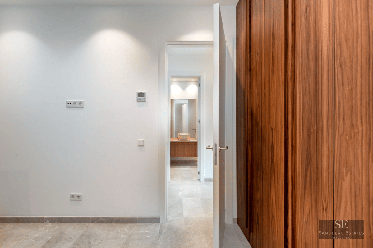 A large wooden built-in wardrobe next to an open door leading to a modern bathroom with a vessel sink.