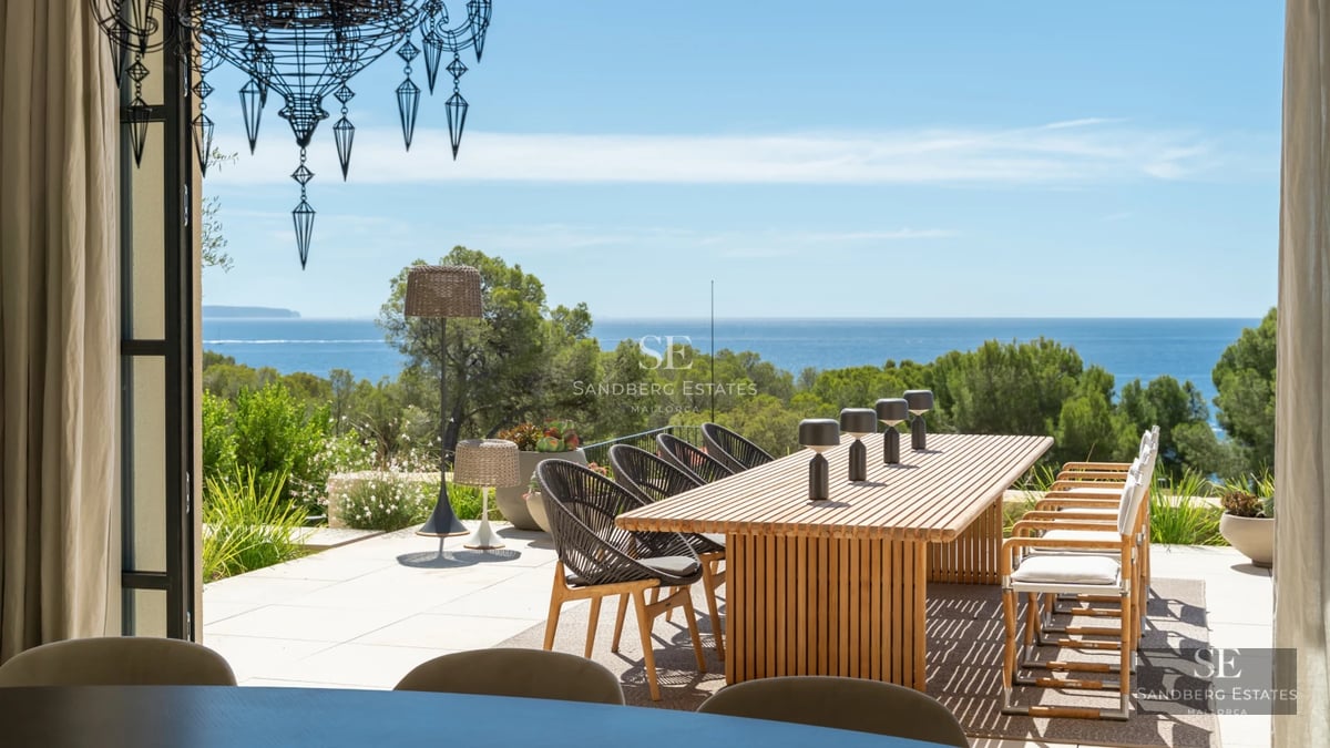 Spacious balcony featuring wooden flooring, glass railing, and panoramic sea views. Modern furniture and minimalist design.