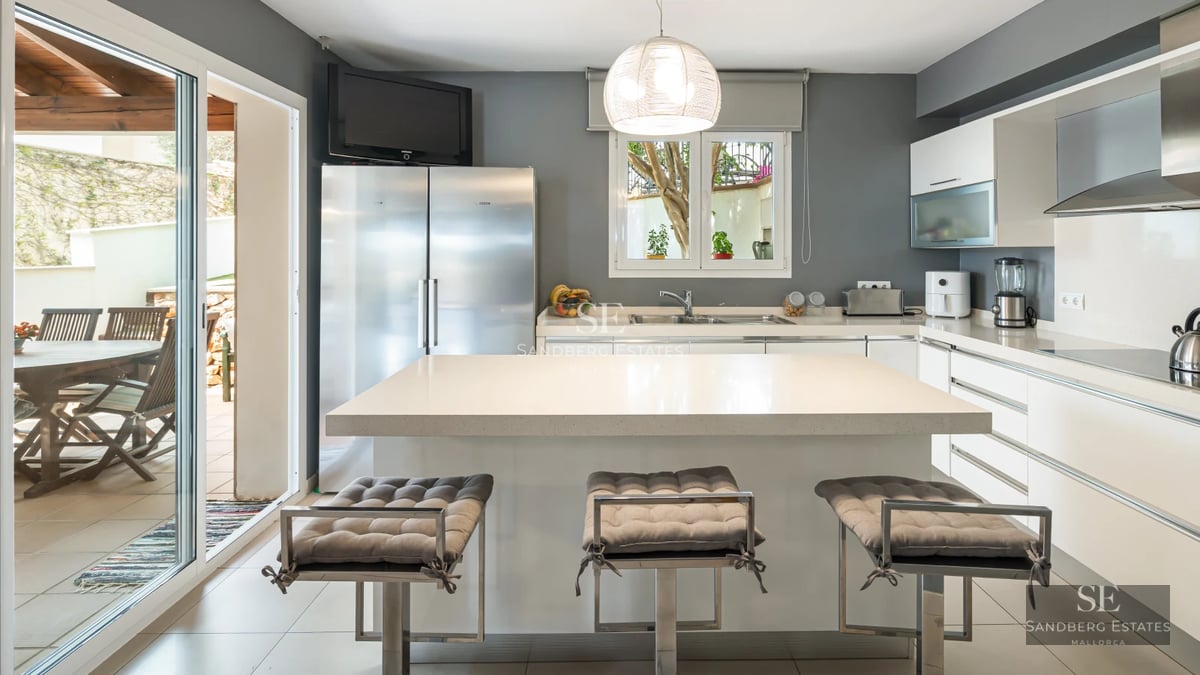 View of a modern pool surrounded by green lawn and contemporary architecture featuring large windows and clear blue sky.