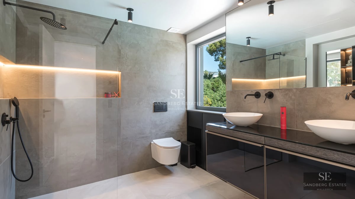 Exterior view of a modern villa featuring a swimming pool, lush gardens, and large windows reflecting sunlight.