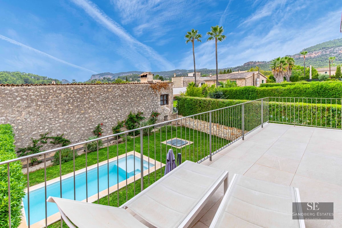 View of infinity pool with sundeck, sun loungers and lush garden. Modern design with ambient lighting.