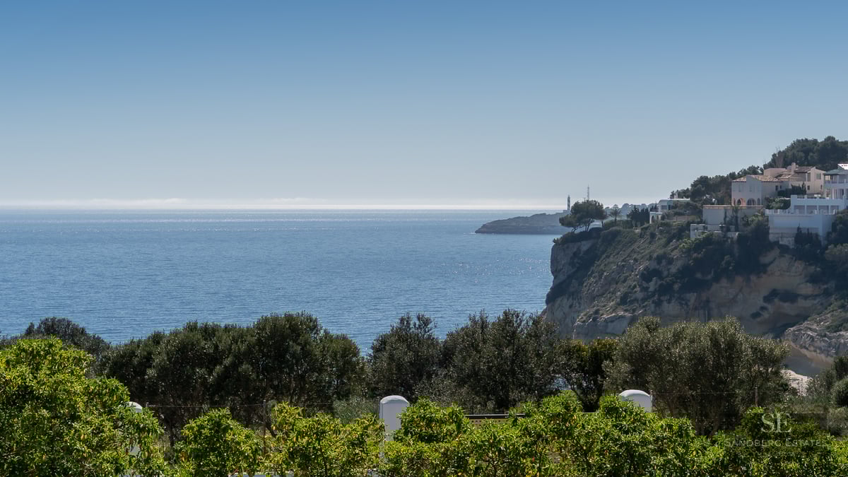 Coastal view with white houses on a cliff and the blue sea under a clear sky.