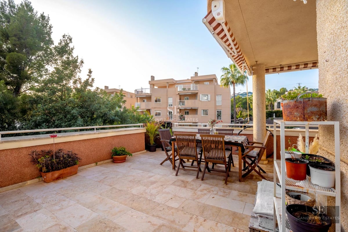 Grand balcon avec vue panoramique sur la mer. Garde-corps en verre, sol en bois et mobilier moderne. Lumineux et spacieux.