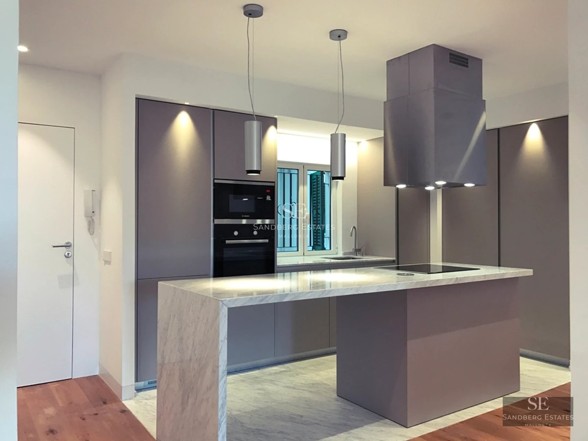 View of an elegant infinity pool surrounded by lush greenery. Modern architecture with clean lines and large windows.