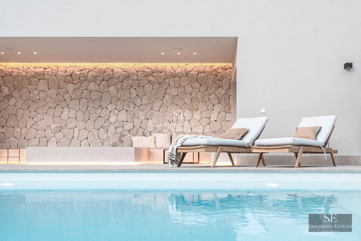 Spacious balcony with glass railing, wooden floor, panoramic view of the city skyline and blue sky at sunset.