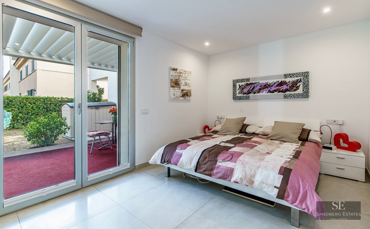 Bright bedroom featuring a double bed, modern art, and a large sliding glass door opening onto a private terrace.